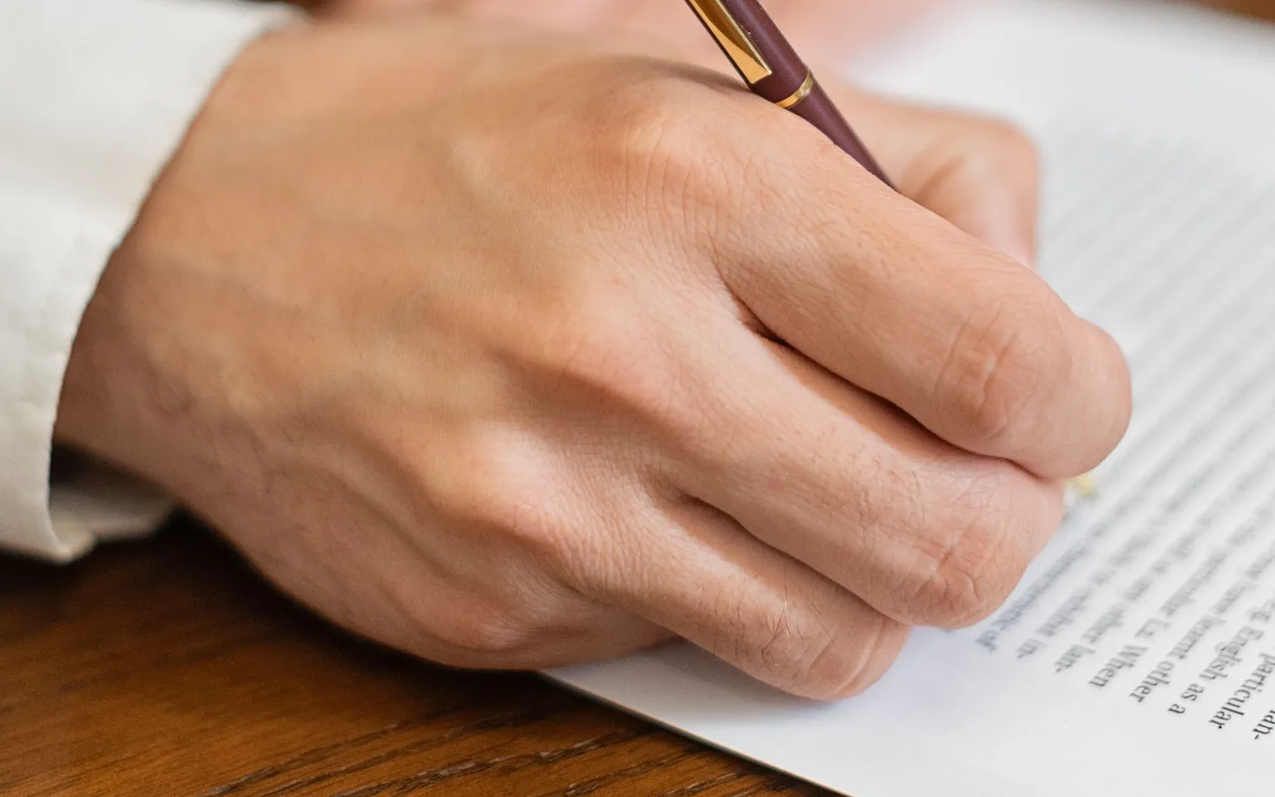 Mână care semnează un document cu pixul