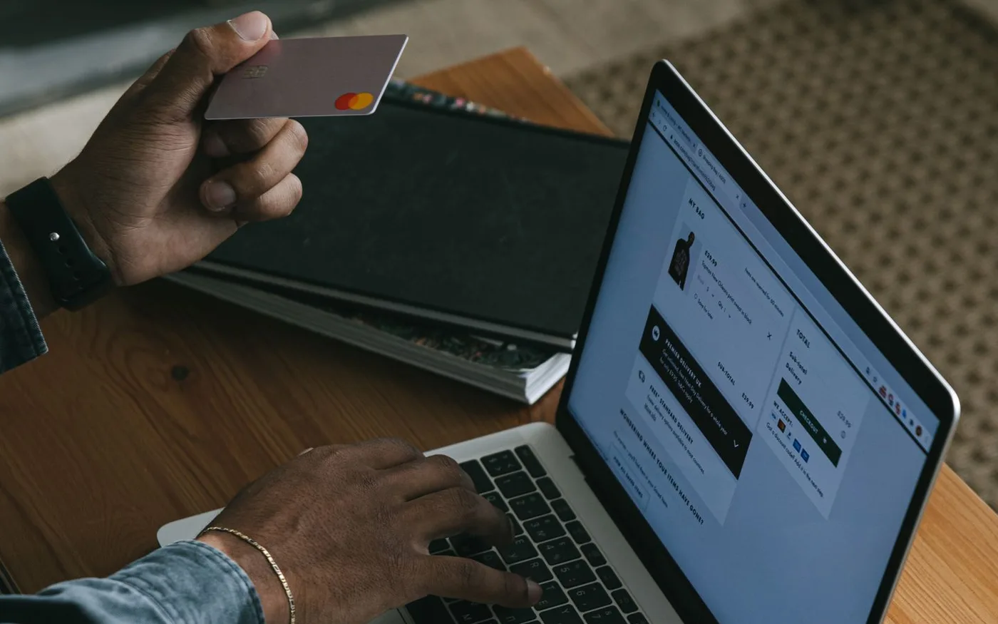 Persoană care finalizează o comandă pe un magazin online, cu cardul în mână