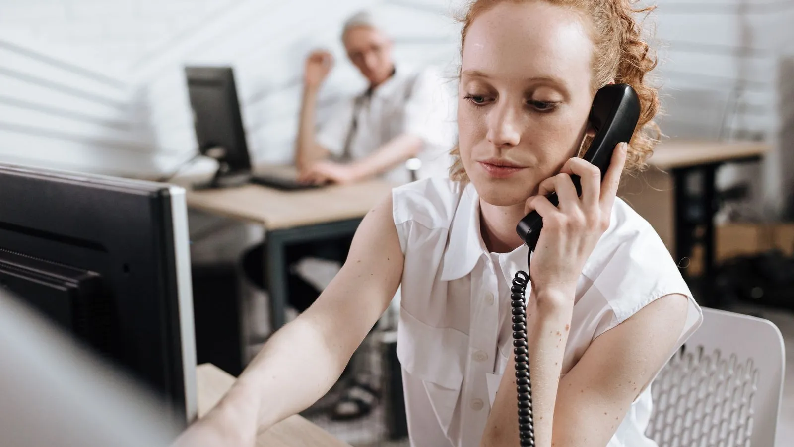 Angajată care vorbește la telefonul fix, la biroul dintr-o firmă