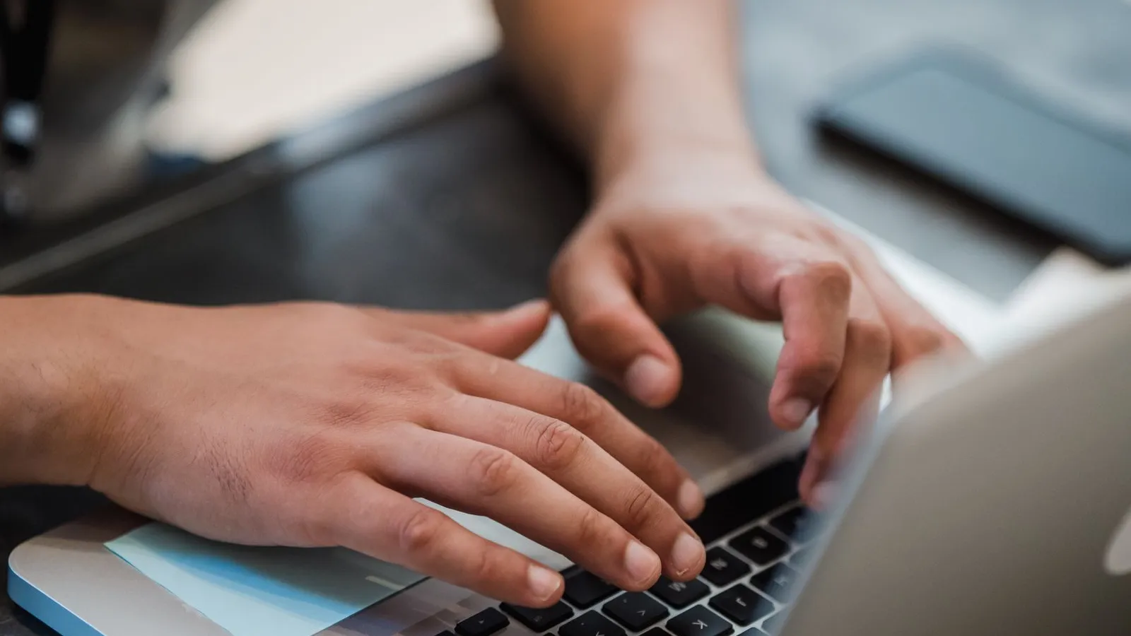 Mâini care tastează pe tastatura unui laptop